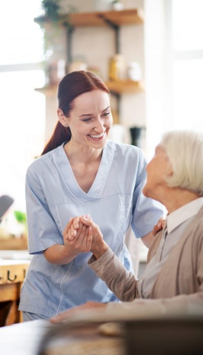 Enjoying work. Beaming caregiver enjoying her work while communicating with pensioner