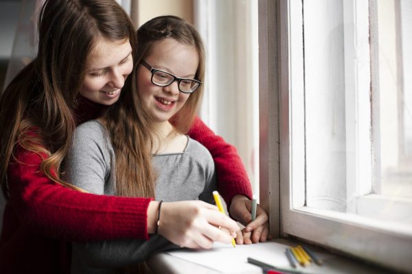 woman-with-happy-girl-with-down-syndrome-drawing